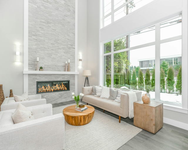 A double height living room with a linear gas fireplace and a wall of windows onto the garden