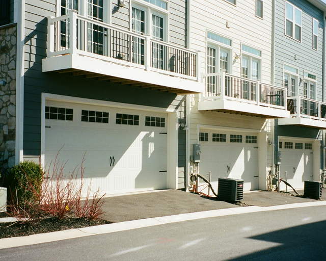 A row of townhouses with private garages and balconies on a quiet residential street